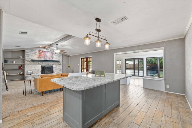 2801 Good Shepherd Dr, Brownwood, TX 76801 - kitchen with light wood-style flooring, gray cabinetry, a ceiling fan, a fireplace, and a center island