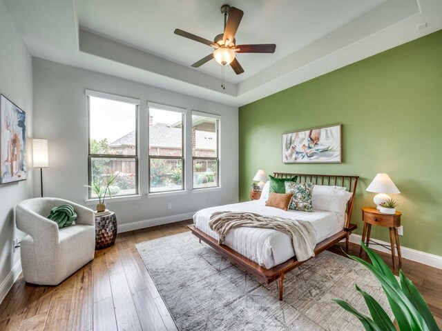 7621 Newtown, The Colony, TX 75056 - bedroom with a raised ceiling, hardwood / wood-style flooring, and a ceiling fan