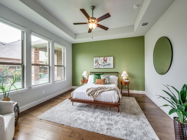 7621 Newtown, The Colony, TX 75056 - bedroom with a tray ceiling, wood finished floors, and a ceiling fan