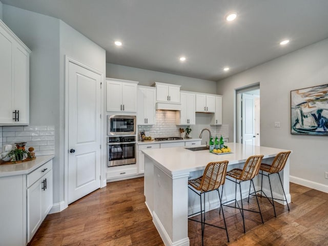 7621 Newtown, The Colony, TX 75056 - kitchen with stainless steel appliances, dark wood-type flooring, a kitchen island with sink, backsplash, and recessed lighting