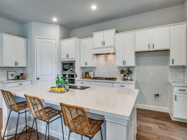7621 Newtown, The Colony, TX 75056 - kitchen with decorative backsplash, white cabinetry, an island with sink, and recessed lighting