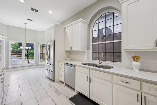 4616 Heatherbrook Ln, Grand Prairie, TX 75052 - kitchen featuring appliances with stainless steel finishes, a sink, a chandelier, white cabinetry, and light countertops