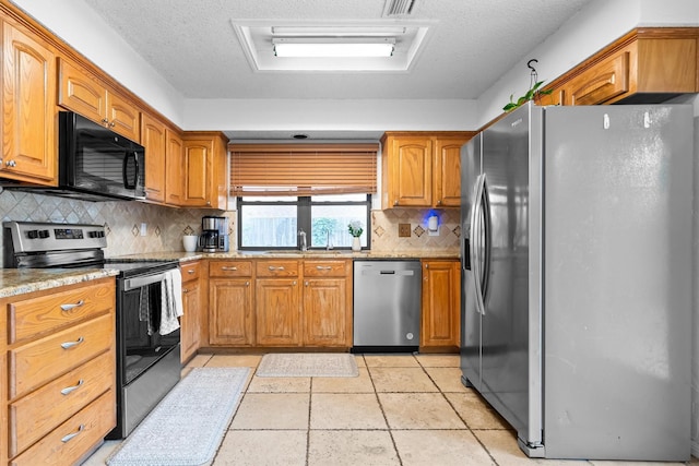 818 Placid Dr, Mesquite, TX 75150 - kitchen featuring appliances with stainless steel finishes, a sink, brown cabinets, and a textured ceiling