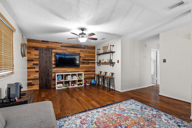 818 Placid Dr, Mesquite, TX 75150 - living area featuring ceiling fan, wood finished floors, wood walls, a textured ceiling, and baseboards