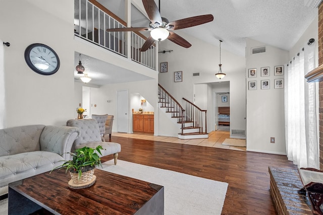 818 Placid Dr, Mesquite, TX 75150 - living room featuring stairs, a ceiling fan, light wood-type flooring, high vaulted ceiling, and a textured ceiling