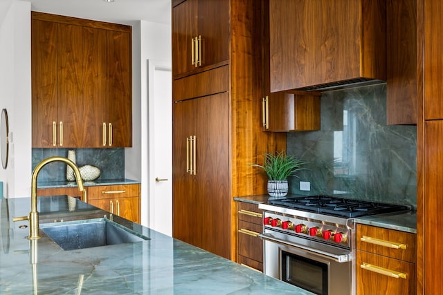 3909 Hawthorne Ave Unit 101, Dallas, TX 75219 - kitchen with high end stainless steel range oven, modern cabinets, a sink, backsplash, and brown cabinets