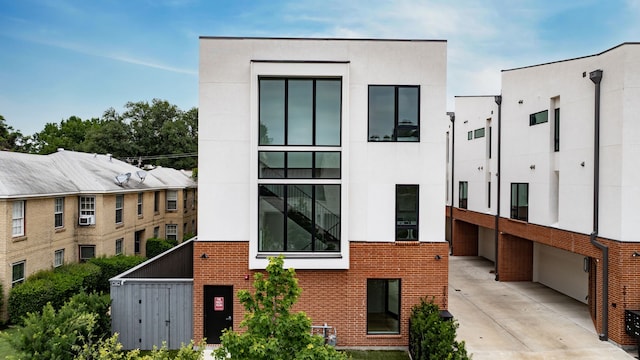3909 Hawthorne Ave Unit 101, Dallas, TX 75219 - view of front facade with brick siding, driveway, a garage, and stucco siding