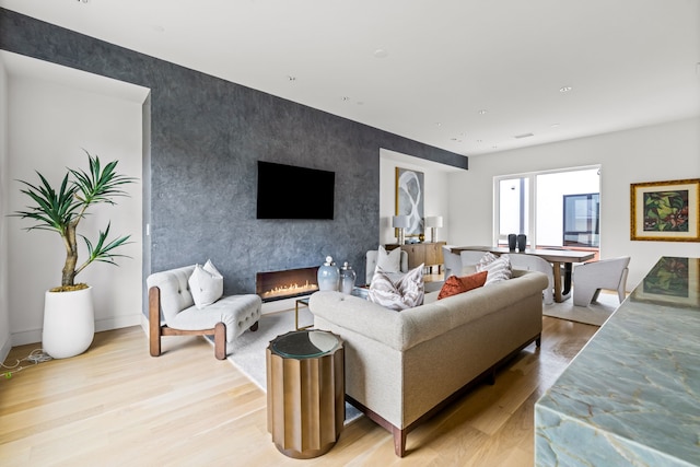 3909 Hawthorne Ave Unit 101, Dallas, TX 75219 - living room with an accent wall, light wood-type flooring, a fireplace, and baseboards