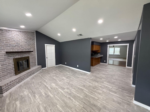 137 W 6th St, Krum, TX 76249 - unfurnished living room featuring lofted ceiling, a brick fireplace, baseboards, and light wood-style flooring
