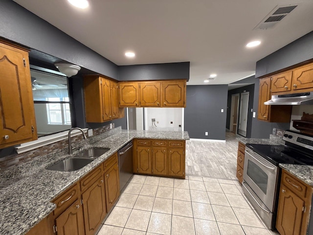 137 W 6th St, Krum, TX 76249 - kitchen with stainless steel appliances, under cabinet range hood, a sink, brown cabinetry, and a peninsula