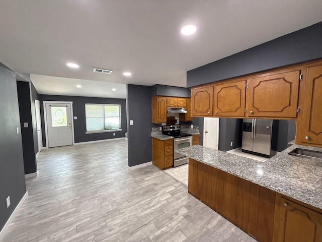 137 W 6th St, Krum, TX 76249 - kitchen with stainless steel appliances, brown cabinets, under cabinet range hood, baseboards, and recessed lighting