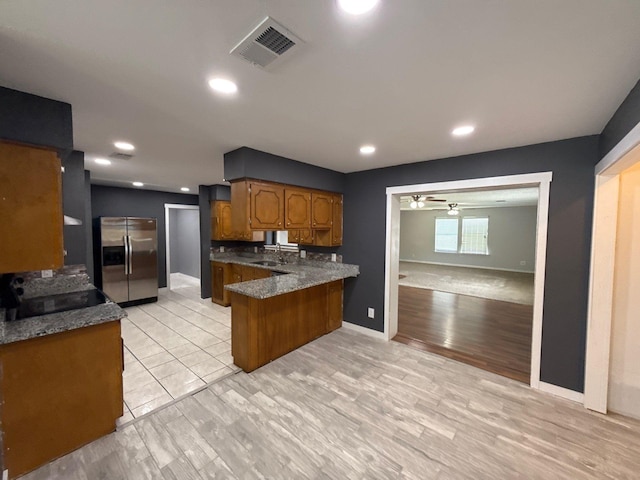 137 W 6th St, Krum, TX 76249 - kitchen featuring stainless steel fridge with ice dispenser, brown cabinets, a peninsula, a ceiling fan, and light wood-type flooring