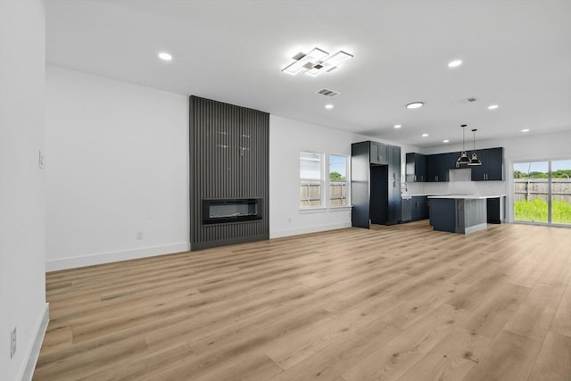 3923 Le May Ave, Dallas, TX 75216 - unfurnished living room featuring recessed lighting, light wood-type flooring, baseboards, and a glass covered fireplace