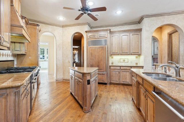 9922 Lakeway Ct, Dallas, TX 75230 - kitchen with arched walkways, high end appliances, a ceiling fan, a sink, and light wood-style floors