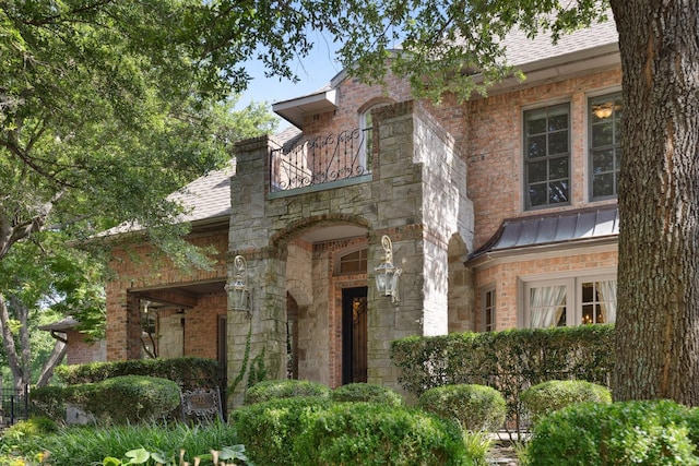 9922 Lakeway Ct, Dallas, TX 75230 - english style home featuring a standing seam roof, a balcony, roof with shingles, and stone siding