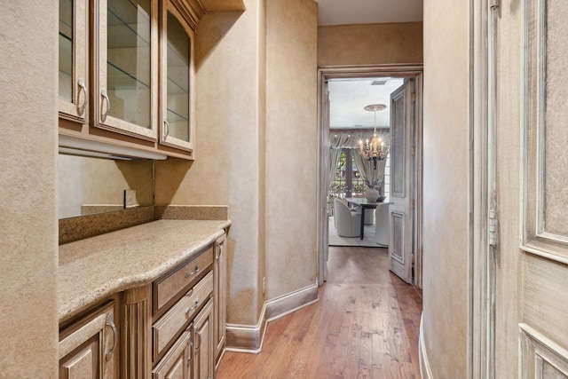 9922 Lakeway Ct, Dallas, TX 75230 - bar featuring light wood-style floors, a chandelier, and baseboards