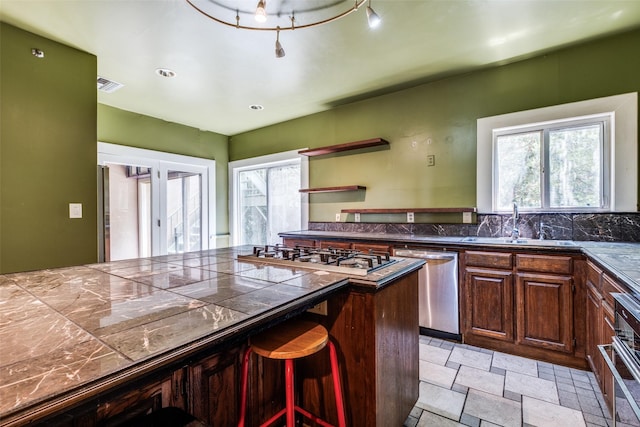 905 Liberty St, Dallas, TX 75204 - kitchen featuring appliances with stainless steel finishes, a sink, light stone finish floors, dark countertops, and open shelves
