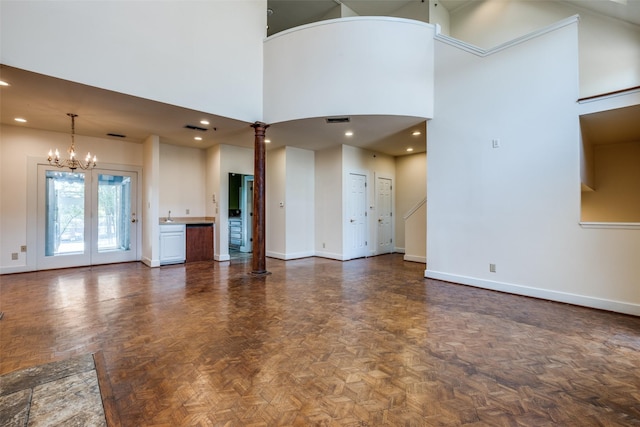 905 Liberty St, Dallas, TX 75204 - unfurnished living room with baseboards, a towering ceiling, a chandelier, decorative columns, and a sink