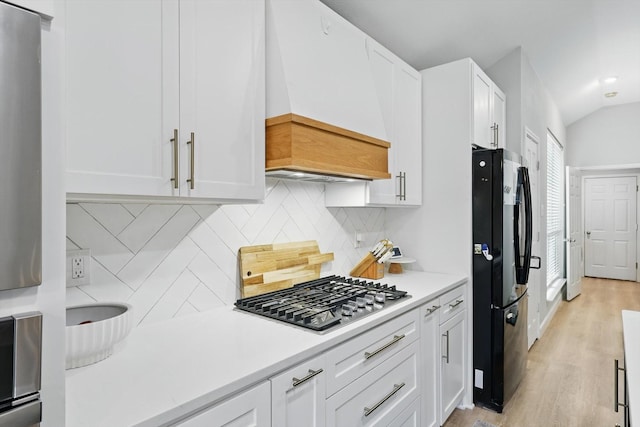 15429 Calico Ct, Frisco, TX 75035 - kitchen with freestanding refrigerator, premium range hood, stainless steel gas cooktop, white cabinets, and light countertops