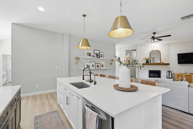 15429 Calico Ct, Frisco, TX 75035 - kitchen with a sink, dishwasher, light wood-type flooring, a ceiling fan, and a brick fireplace