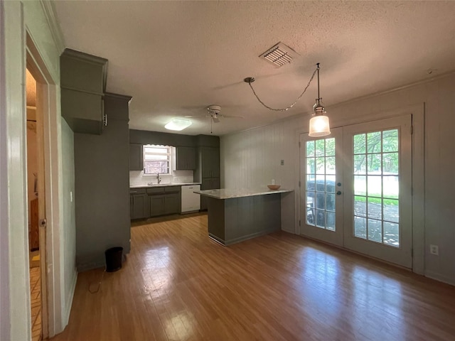 310 Lancashire Dr, Bossier City, LA 71111 - kitchen with healthy amount of natural light, light wood-type flooring, a peninsula, light countertops, and a textured ceiling