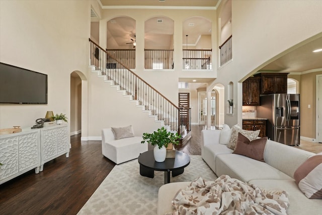 14759 Huffman Ln, Frisco, TX 75035 - living area featuring arched walkways, wood finished floors, a towering ceiling, baseboards, and stairway