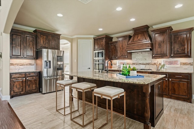 14759 Huffman Ln, Frisco, TX 75035 - kitchen featuring appliances with stainless steel finishes, arched walkways, custom range hood, backsplash, and a breakfast bar area