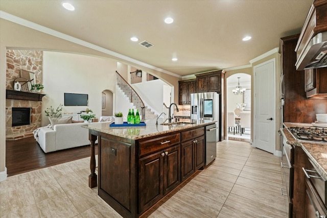 14759 Huffman Ln, Frisco, TX 75035 - kitchen featuring arched walkways, appliances with stainless steel finishes, a center island with sink, a chandelier, and crown molding