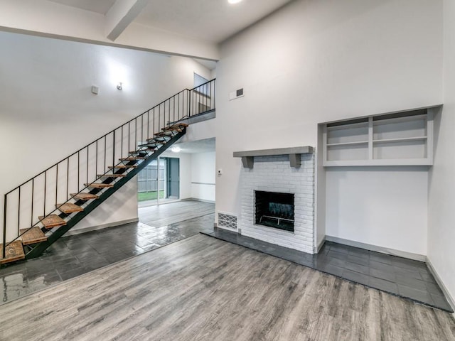 100 Trellis Pl Unit 102, Richardson, TX 75081 - unfurnished living room featuring stairway, wood finished floors, a high ceiling, baseboards, and a fireplace