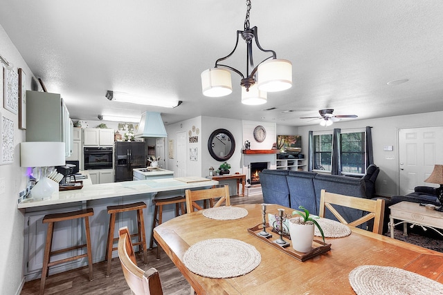 5730 Rendon Estates Rd, Mansfield, TX 76063 - dining space featuring a textured ceiling, a ceiling fan, wood finished floors, and a lit fireplace