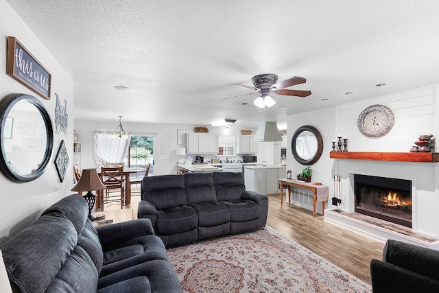 5730 Rendon Estates Rd, Mansfield, TX 76063 - living area with a lit fireplace, a ceiling fan, light wood-style floors, and a textured ceiling