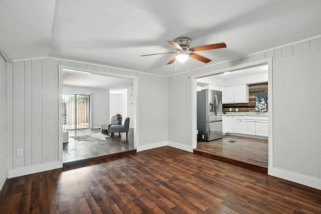 2729 Caton Pl, Abilene, TX 79605 - unfurnished living room with ceiling fan, baseboards, dark wood-style floors, vaulted ceiling, and a textured ceiling