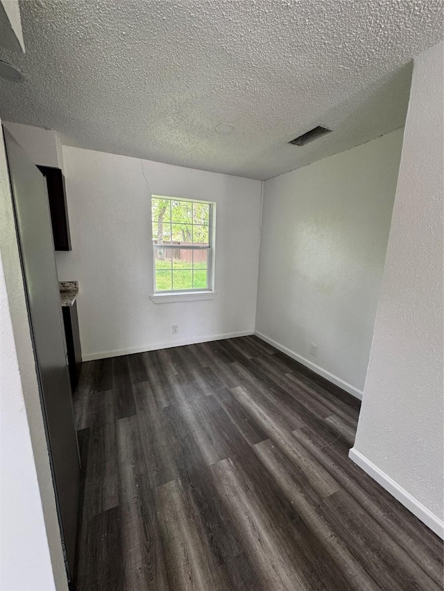 2441 Lindale Ln, Mesquite, TX 75149 - spare room with a textured ceiling, dark wood-style floors, and baseboards