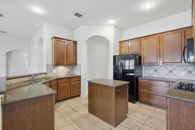 209 Lariat Dr, Fate, TX 75087 - kitchen with black appliances, a sink, arched walkways, backsplash, and recessed lighting