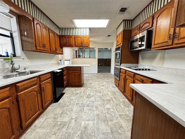 1050 35th St NE, Paris, TX 75462 - kitchen with black appliances, a sink, a textured ceiling, a peninsula, and light countertops
