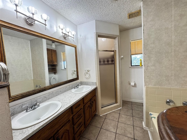 1050 35th St NE, Paris, TX 75462 - bathroom featuring a shower stall, a garden tub, double vanity, a textured ceiling, and tile patterned floors