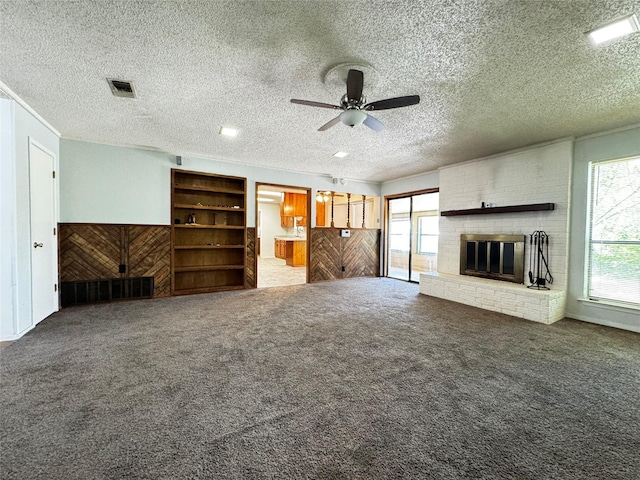 1050 35th St NE, Paris, TX 75462 - unfurnished living room featuring a ceiling fan, carpet flooring, a fireplace, and a textured ceiling
