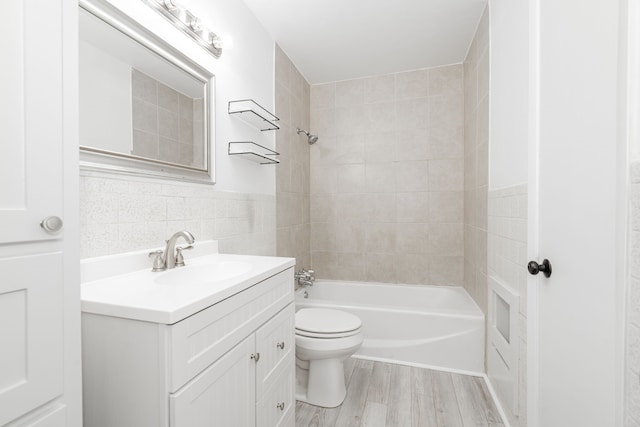 2401 Gilmer St, Caddo Mills, TX 75135 - bathroom featuring toilet, vanity, tile walls, wood finished floors, and shower / washtub combination