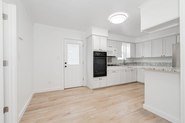 2401 Gilmer St, Caddo Mills, TX 75135 - kitchen with black oven, a warming drawer, light wood-style flooring, crown molding, and white cabinetry