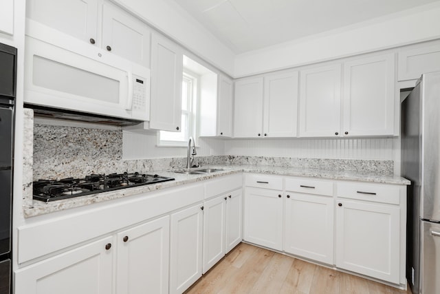 2401 Gilmer St, Caddo Mills, TX 75135 - kitchen featuring white microwave, freestanding refrigerator, a sink, black gas cooktop, and white cabinets
