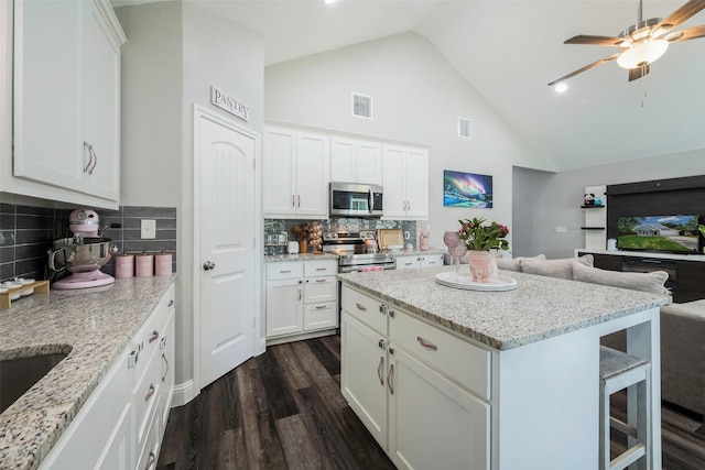 1004 San Jacinto St, Terrell, TX 75160 - kitchen with appliances with stainless steel finishes, dark wood finished floors, high vaulted ceiling, a breakfast bar area, and open floor plan