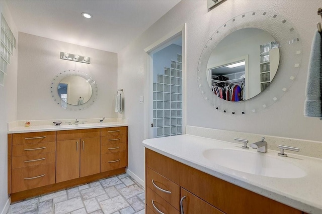 3108 Landershire Ln, Plano, TX 75023 - bathroom featuring two vanities, a spacious closet, recessed lighting, baseboards, and brick patterned floors