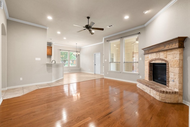 401 Shumard Oak Trl, Keller, TX 76248 - unfurnished living room featuring ceiling fan, a glass covered fireplace, crown molding, a chandelier, and light wood-style floors