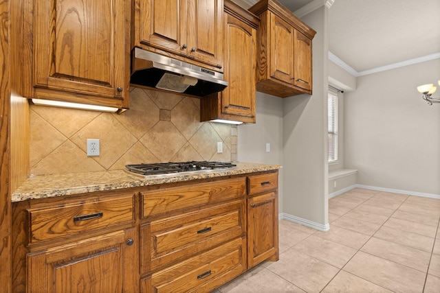 401 Shumard Oak Trl, Keller, TX 76248 - kitchen featuring under cabinet range hood, stainless steel gas stovetop, ornamental molding, decorative backsplash, and brown cabinets