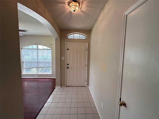 4102 Baccarat Dr, Garland, TX 75043 - foyer featuring a textured ceiling, arched walkways, baseboards, and light tile patterned floors
