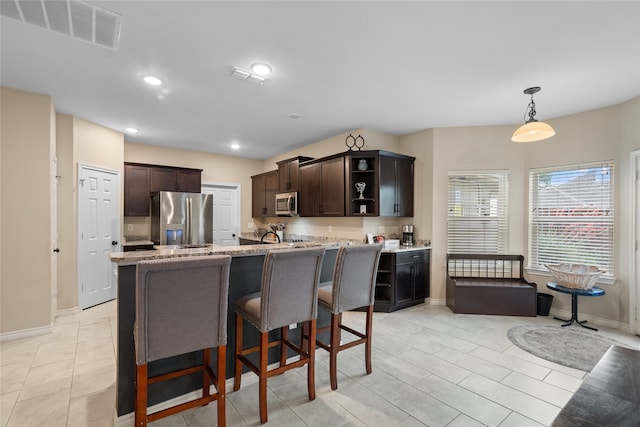8208 Burleigh St, Frisco, TX 75035 - kitchen featuring appliances with stainless steel finishes, dark brown cabinetry, open shelves, a kitchen bar, and baseboards