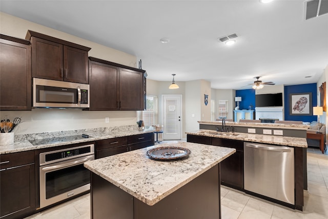 8208 Burleigh St, Frisco, TX 75035 - kitchen with appliances with stainless steel finishes, a kitchen island, open floor plan, dark brown cabinets, and light tile patterned flooring