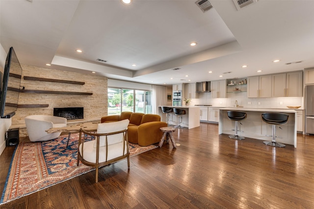 4047 Calculus Dr, Dallas, TX 75244 - living area featuring a raised ceiling, dark wood-type flooring, a stone fireplace, and recessed lighting