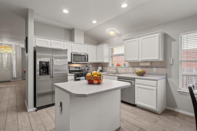12804 Council Bluff Dr, Austin, TX 78727 - kitchen featuring appliances with stainless steel finishes, tasteful backsplash, white cabinets, light wood-style flooring, and a kitchen island