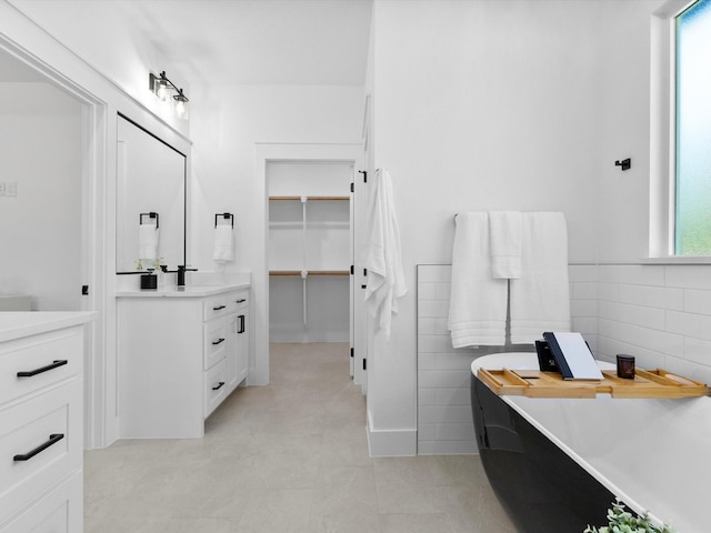 1705 J E, Woody, Springtown, TX 76082 - bathroom featuring vanity, a freestanding tub, a walk in closet, and tile walls